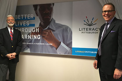 men stand near a poster promoting literacy